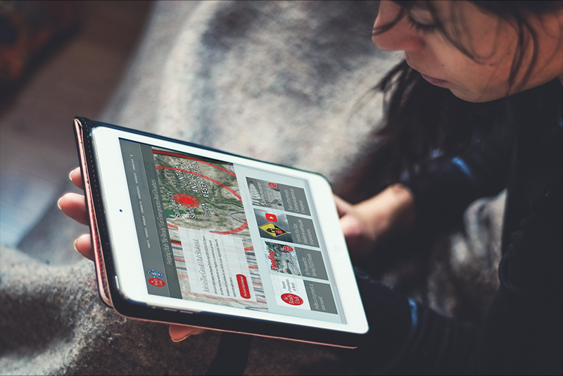 Young woman reading an electronic tablet full of emergency preparedness information.