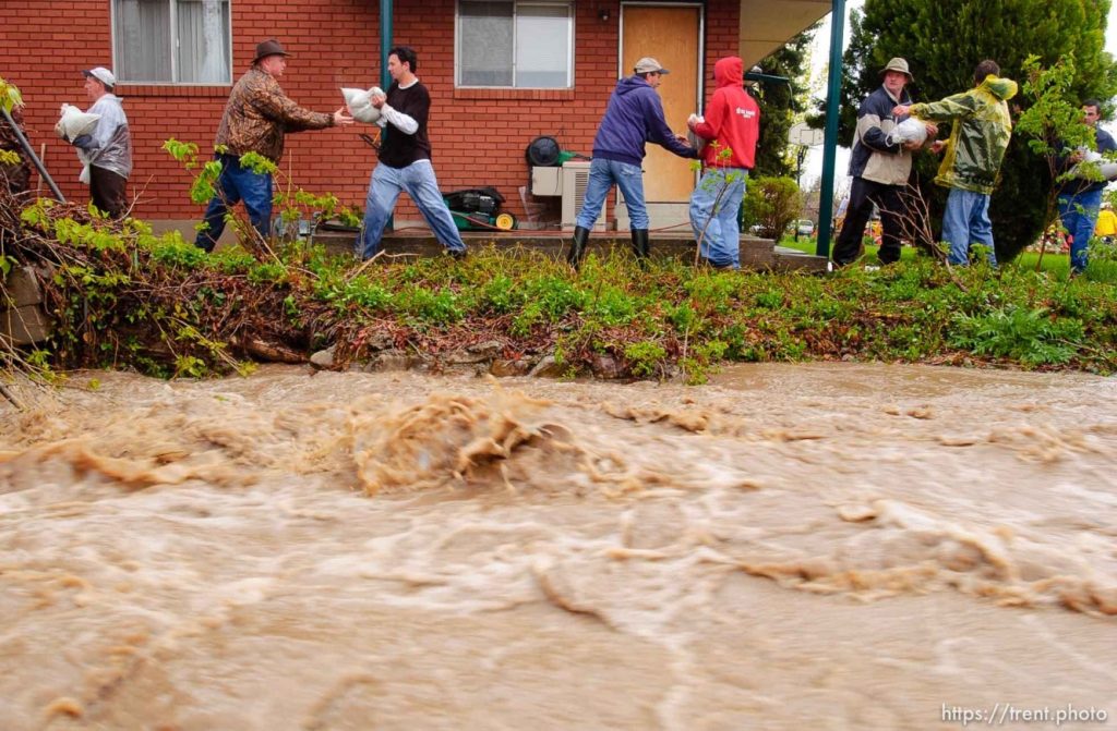 People placing sandbags around a house with rising flood waters